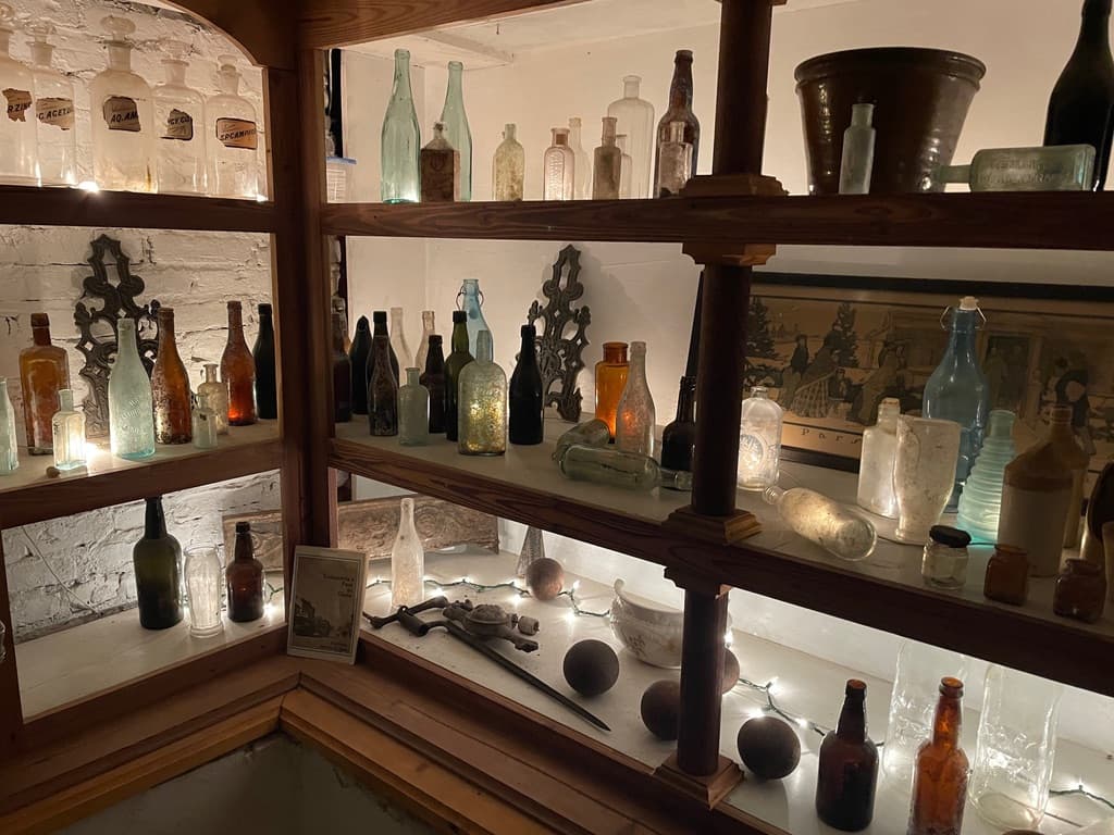 A display of various antique bottles and artifacts illuminated by soft lighting.