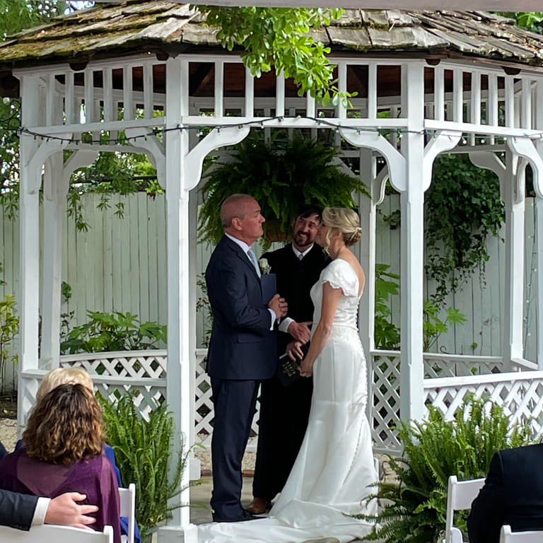 A couple exchanges vows under a gazebo during their wedding ceremony.