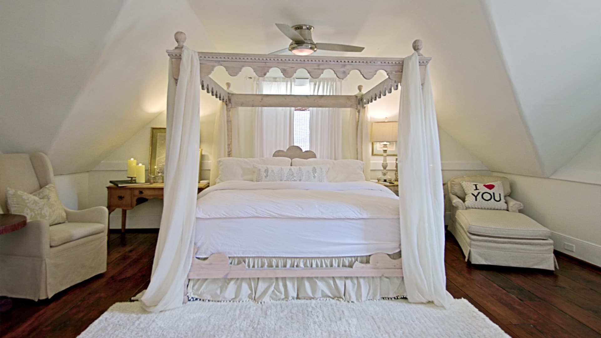 A cozy attic bedroom featuring a four-poster bed, a plush chair, and soft decor.