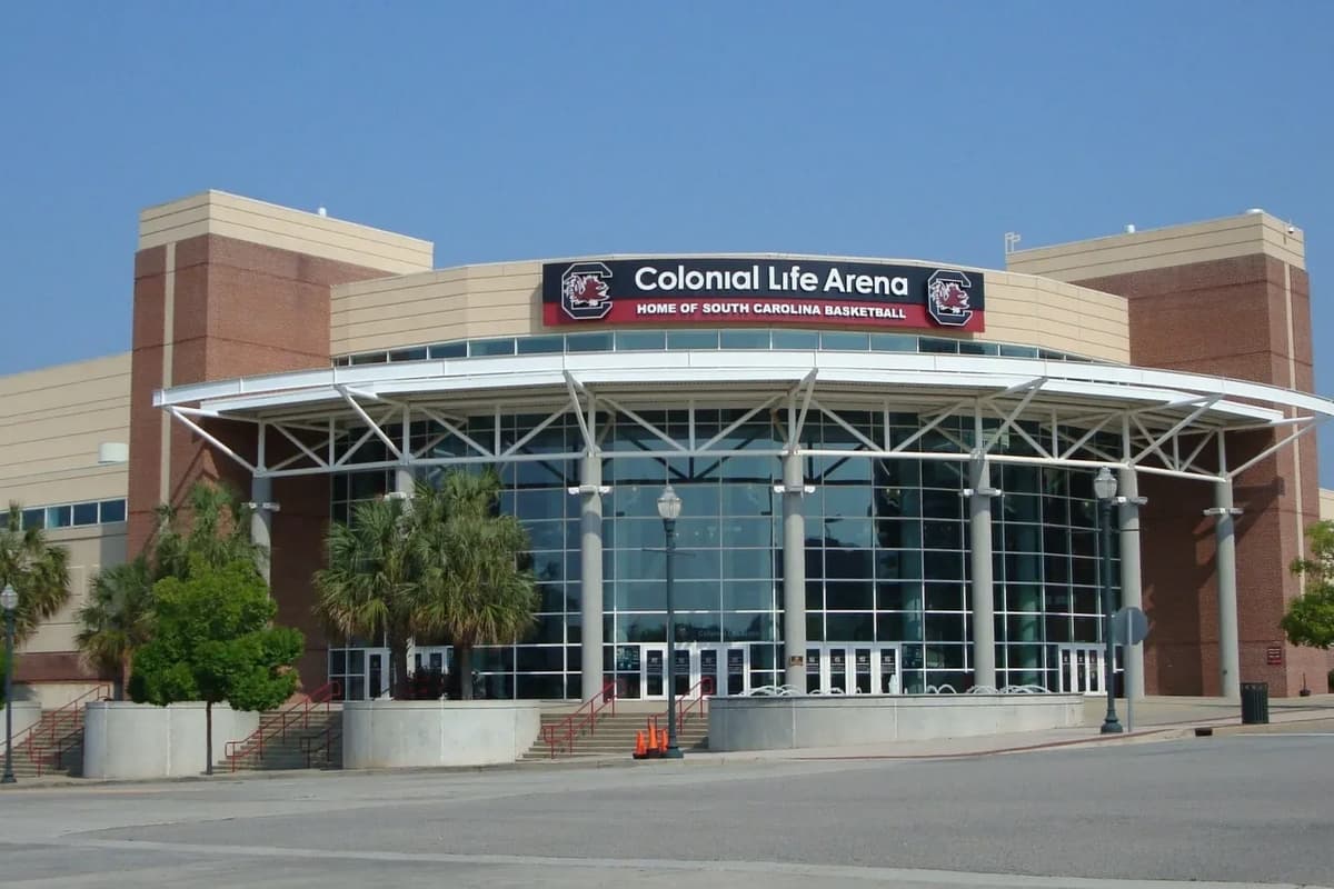 Front view of the Colonial Life Arena, home of South Carolina basketball, featuring a large glass entrance and palm trees.