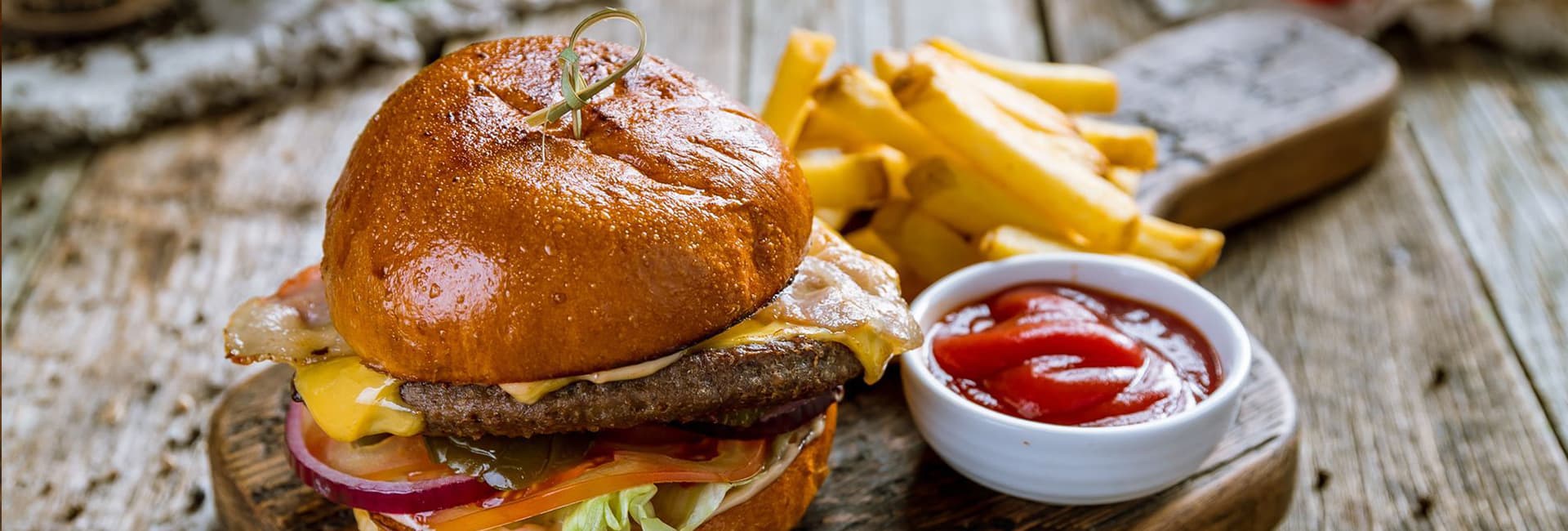A delicious cheeseburger with lettuce, tomato, and onion, served with fries and a side of ketchup.