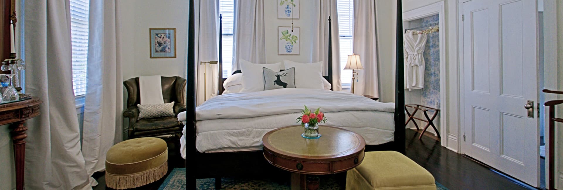 A cozy bedroom featuring a four-poster bed, seating area, and elegant decor.